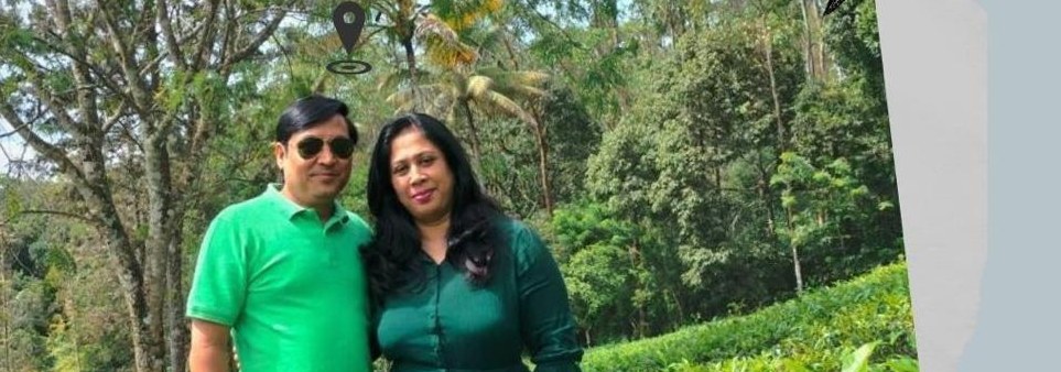 A couple photographed together among greenery on their anniversary trip to Kerala